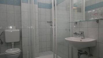 Une salle de bain avec une douche à parois de verre, un lavabo blanc et des toilettes.