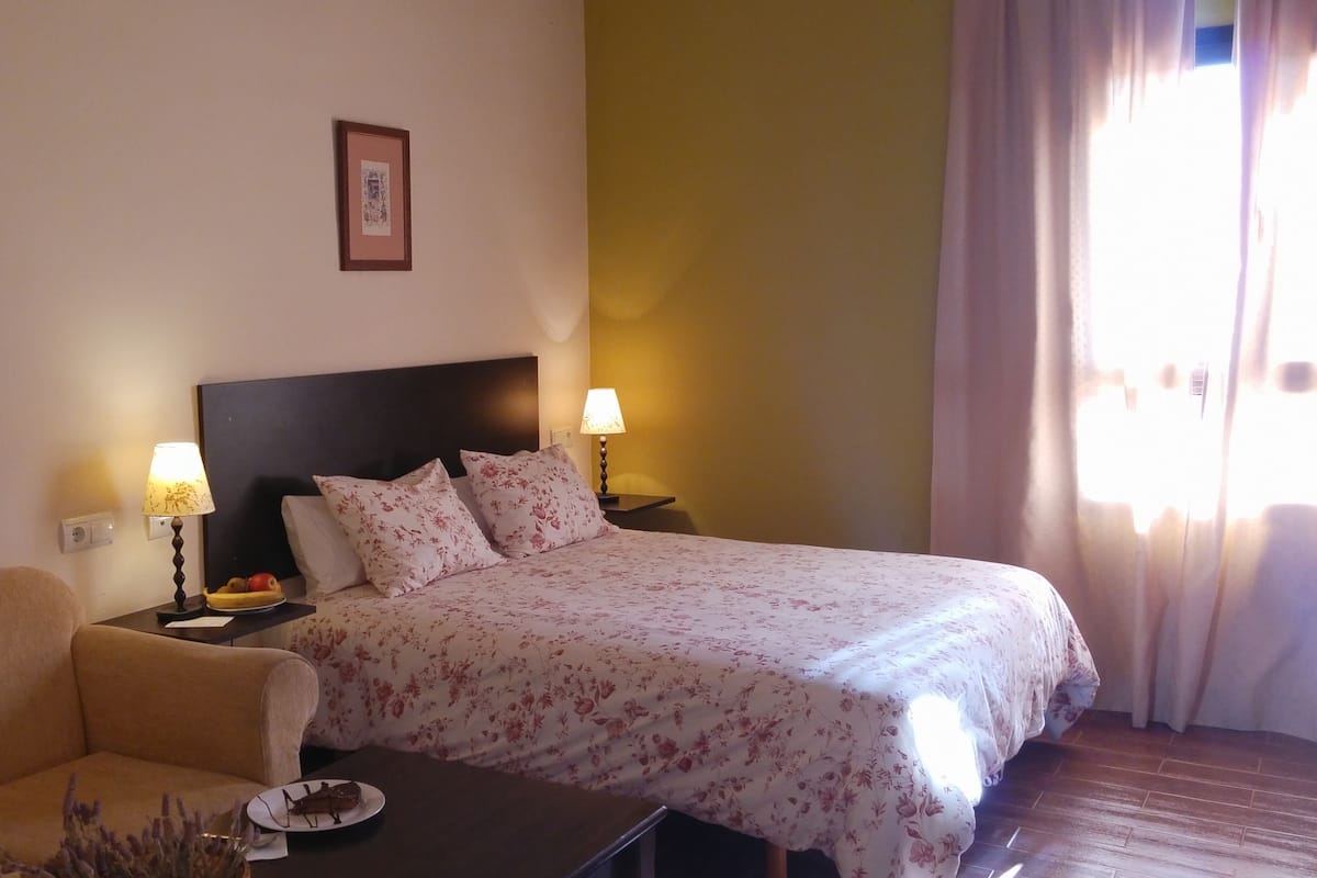 Ein Hotelzimmer mit einem Bett, einem Sofa, einem Nachttisch mit Lampe und einem gerahmten Bild an der Wand.