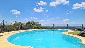 A clear blue swimming pool with a curved edge, surrounded by a concrete deck.