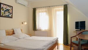 Quarto de hotel com duas camas, uma escrivaninha com cadeira, televisão e janela com cortinas.