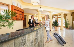 Zona de recepción de un hotel con mostrador de mármol, un escritorio y un sistema de timbre en la pared.