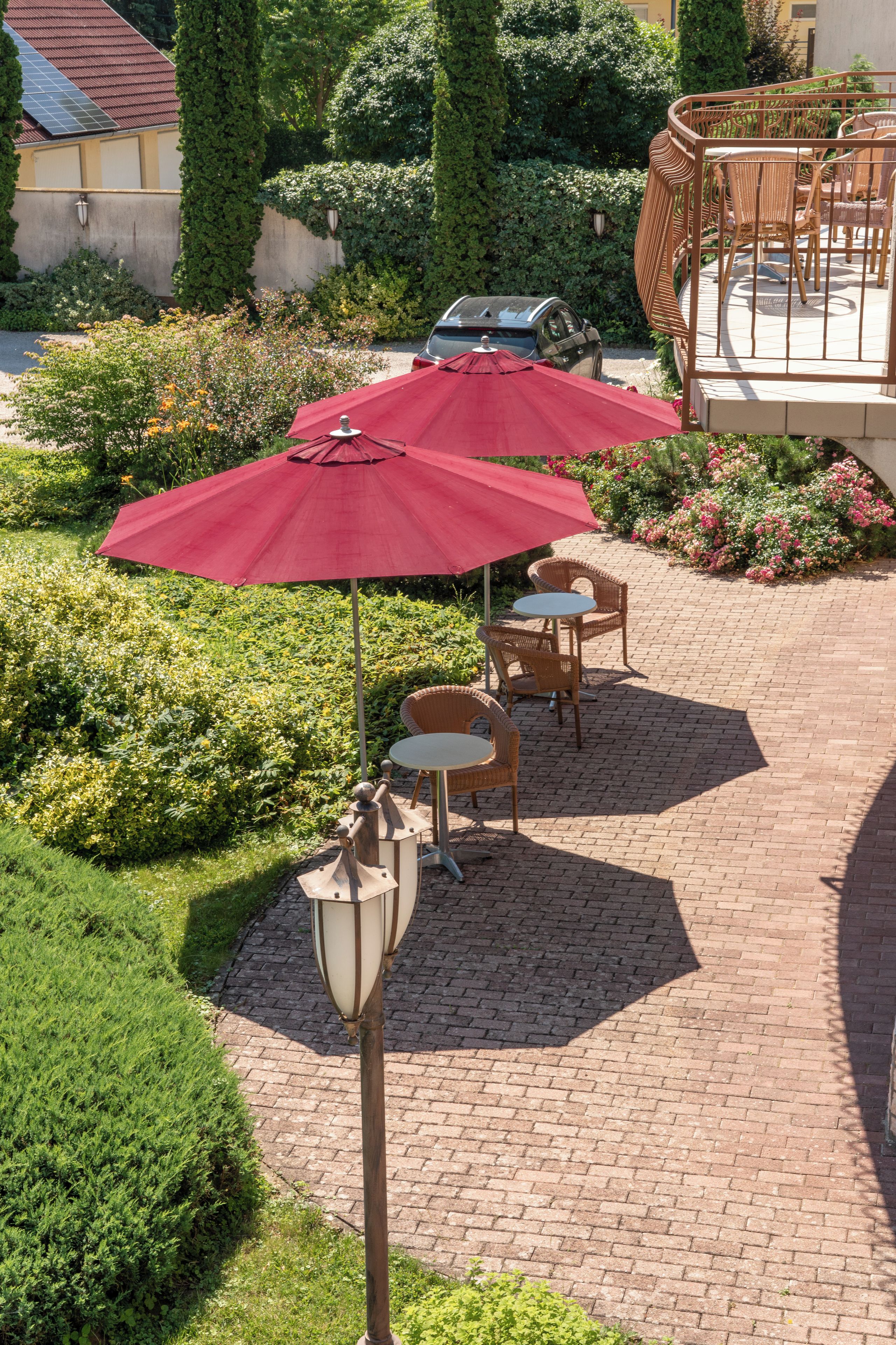 Un espace patio avec un parasol rouge, des chaises en osier et une table.