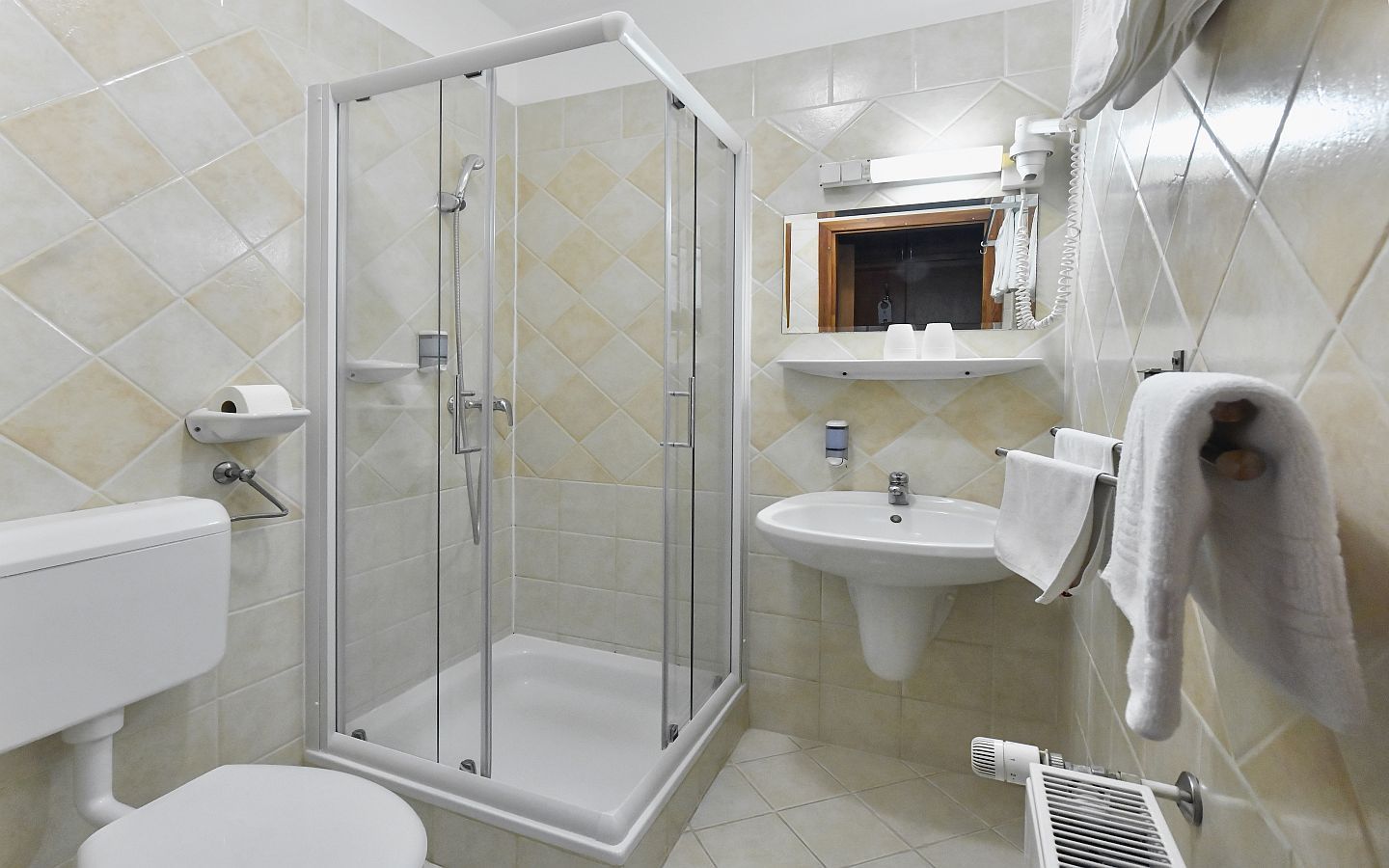 Un baño con ducha envuelta en cristal, inodoro, lavamanos y toallero.