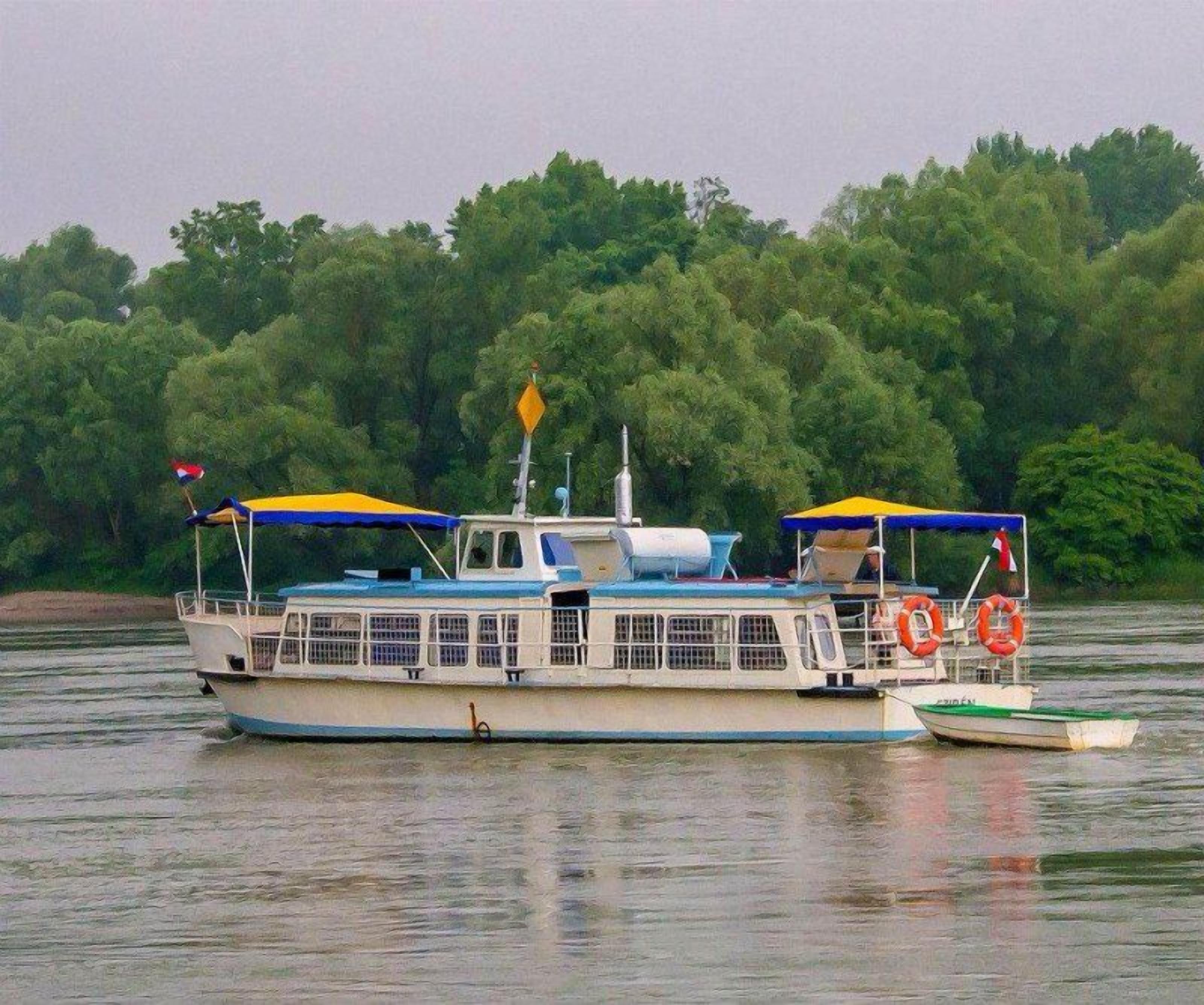 A boat with a cabin, seating area, and lifebuoys.