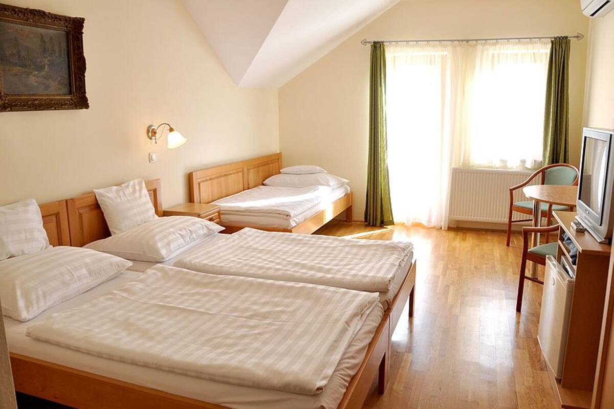 A hotel room with two beds, a television, and a small table.