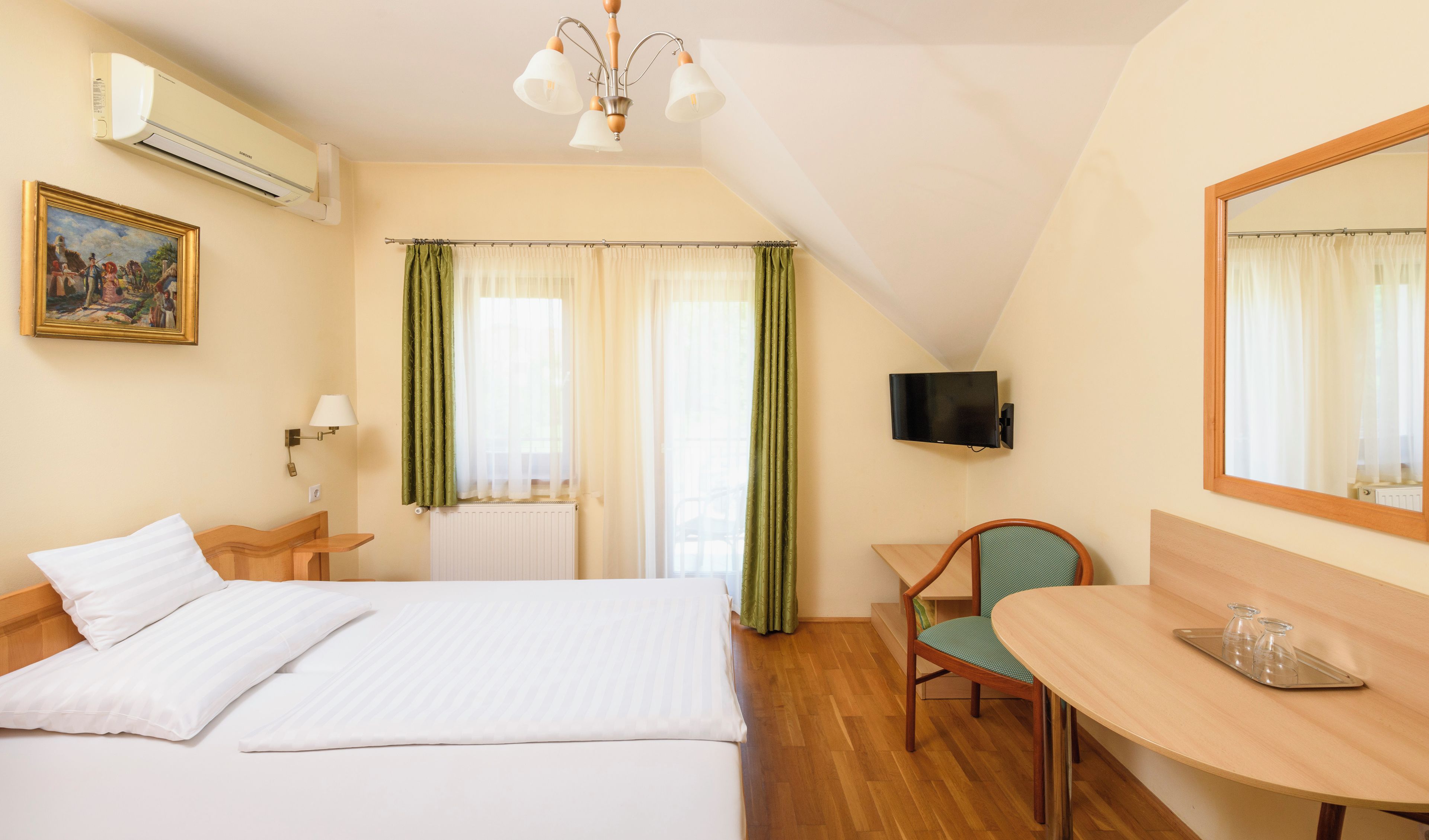 Habitación de hotel con cama, escritorio, silla, televisión y un cuadro en la pared.