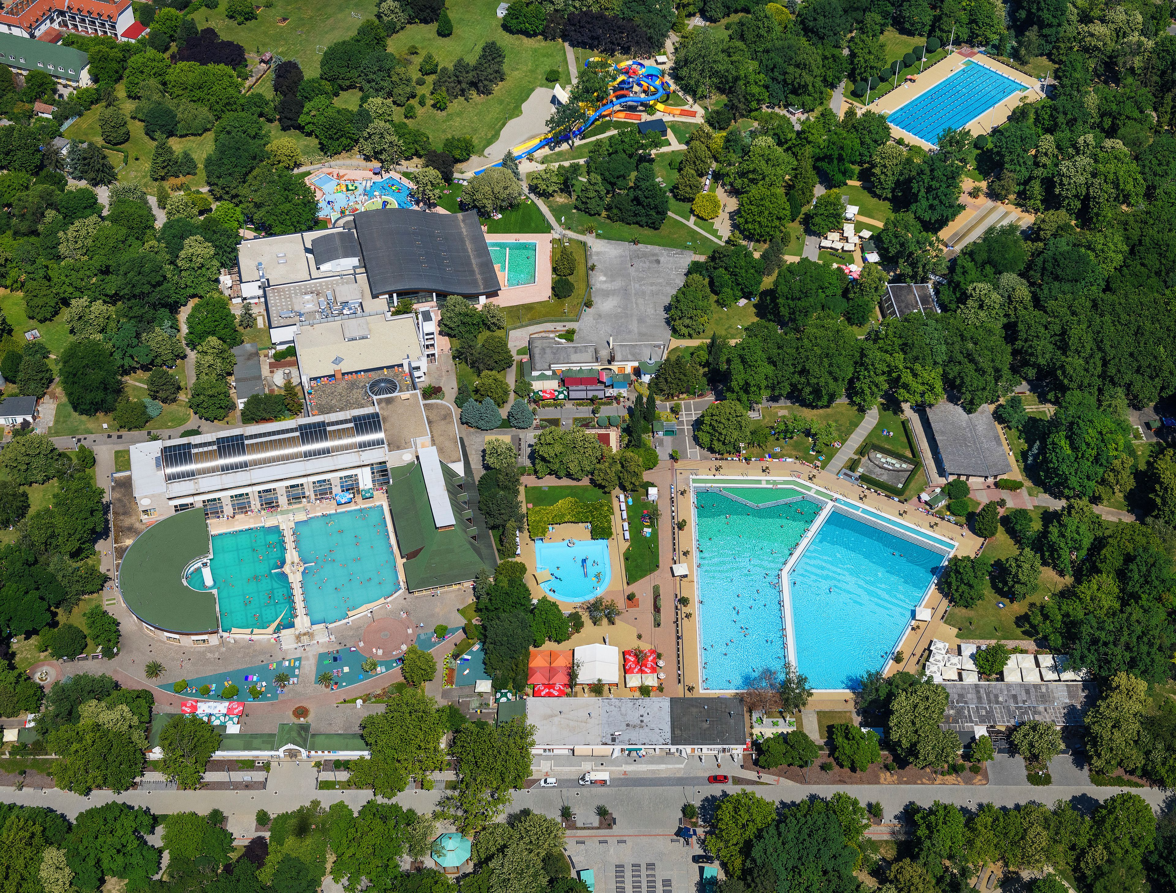 An aerial view of a resort with multiple swimming pools, a water park, and lush greenery.