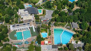 An aerial view of a resort with multiple swimming pools, a water park, and lush greenery.