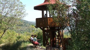 Uma torre de observação de madeira com telhado cônico, com vista para um vale arborizado.