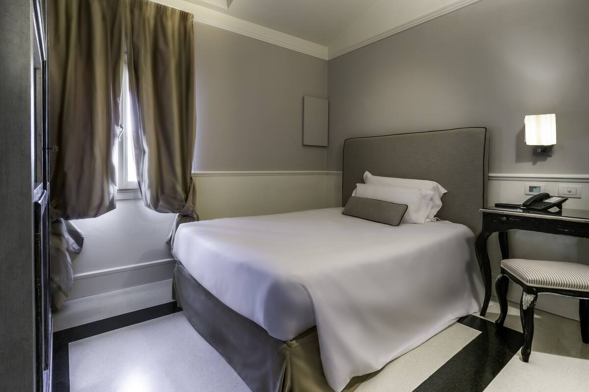 Une chambre d’hôtel avec un lit bien fait, un bureau avec un téléphone et une chaise.