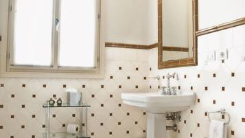 Een badkamer met een raam, een wastafel, een toiletbril en een spiegel.