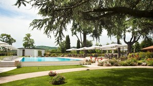 Un espace piscine avec une piscine à l’eau d’un bleu limpide, entourée d’une pelouse bien entretenue et agrémentée de différents coins salon.