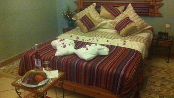 Una cama con cabecera de madera, ropa de cama a rayas y dos toallas blancas con flores púrpuras.