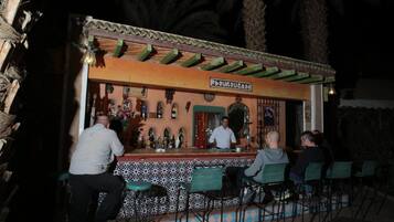 An outdoor bar with a tiled floor and green chairs.