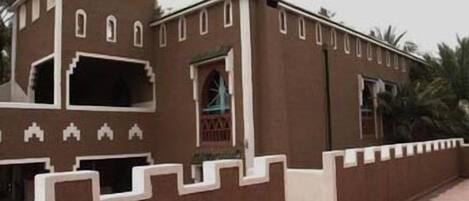 Un edificio tradicional con fachada simétrica, con ventanas de arco y adornos blancos decorativos.