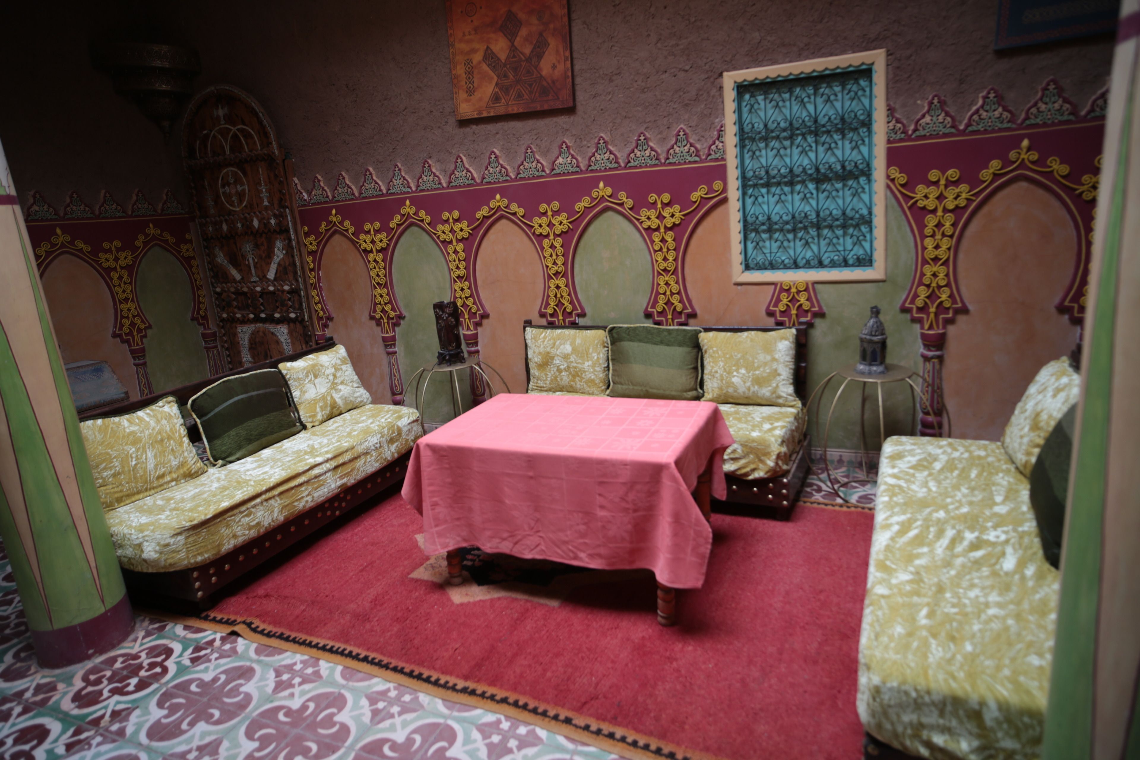 A room with a bed, two sofas, a table, and decorative wall elements.