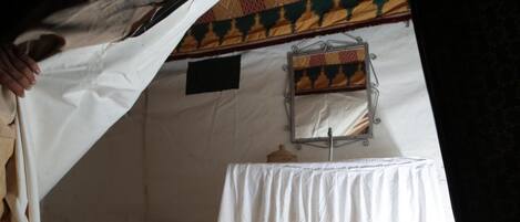 A tent with a white table and a mirror on the wall.