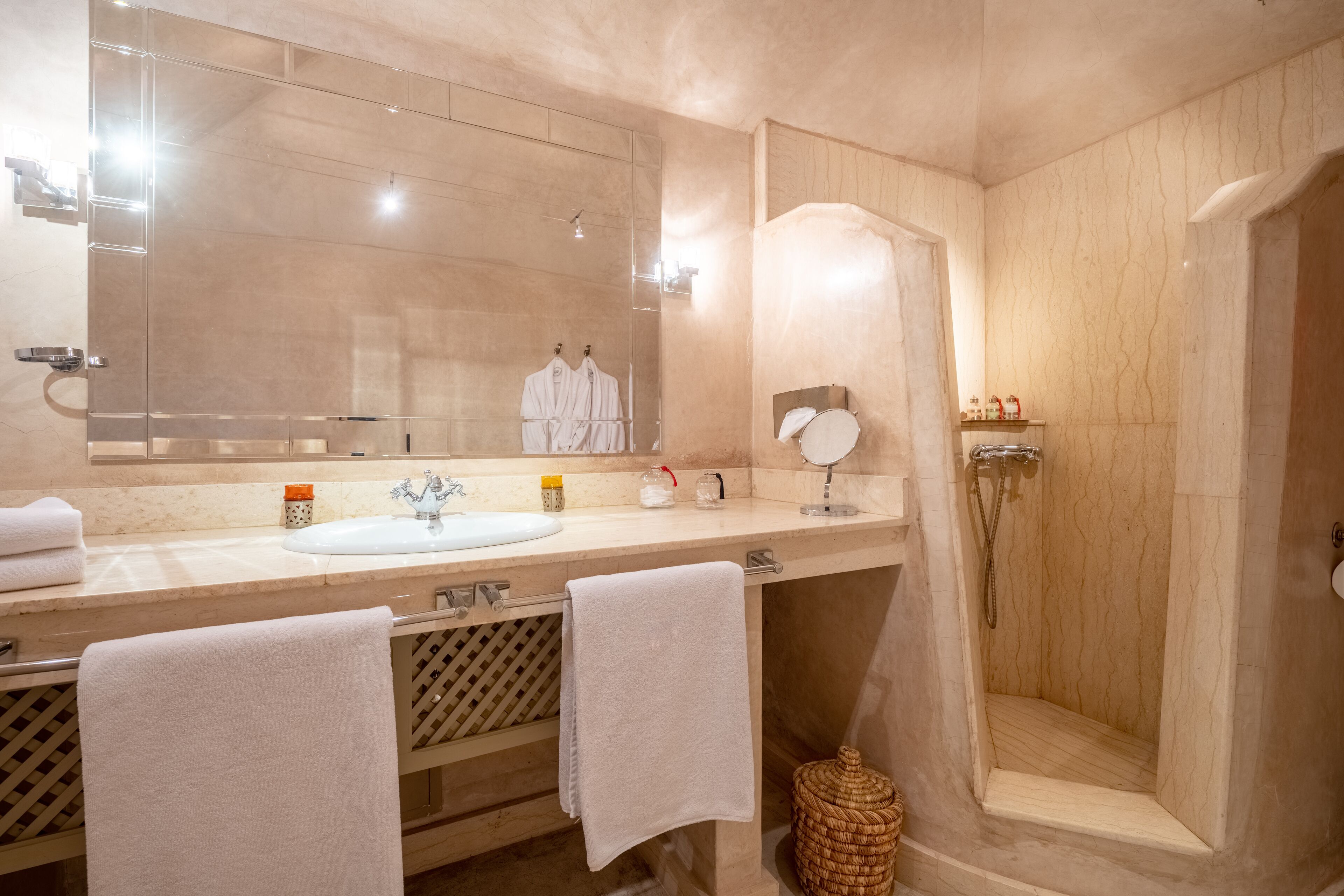 Un baño moderno con un espejo grande, dos lavamanos, una ducha y toallas.