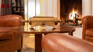 A cozy living room with leather armchairs, a wooden side table, a brass lamp, and a fireplace. - Riad Alma (Marrakech)
