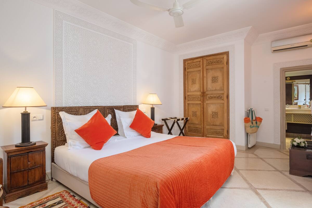 Quarto bem arrumado com uma cama grande, duas luminárias de cabeceira, um guarda-roupa de madeira e um ventilador de teto.