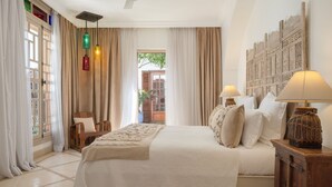 A bedroom with a large bed, two bedside lamps, a wooden headboard, and a view of the outside. - Riad Alma (Marrakech)