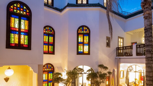 A multi-level building with a pool, outdoor seating, and a staircase leading to a balcony. - Riad Alma (Marrakech)
