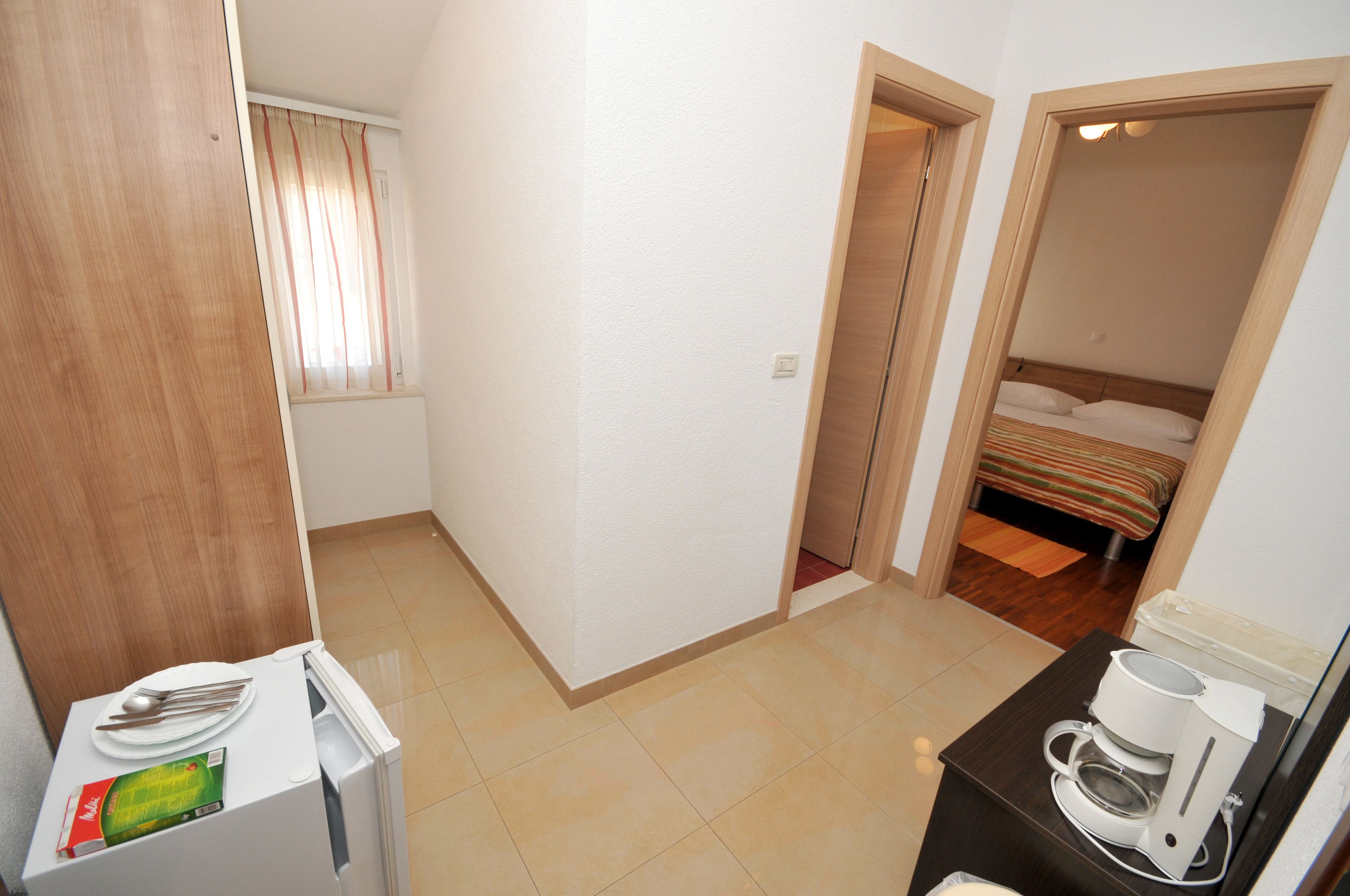 Een compacte hotelkamer met kitchenette, een bed en een klein zithoekje.