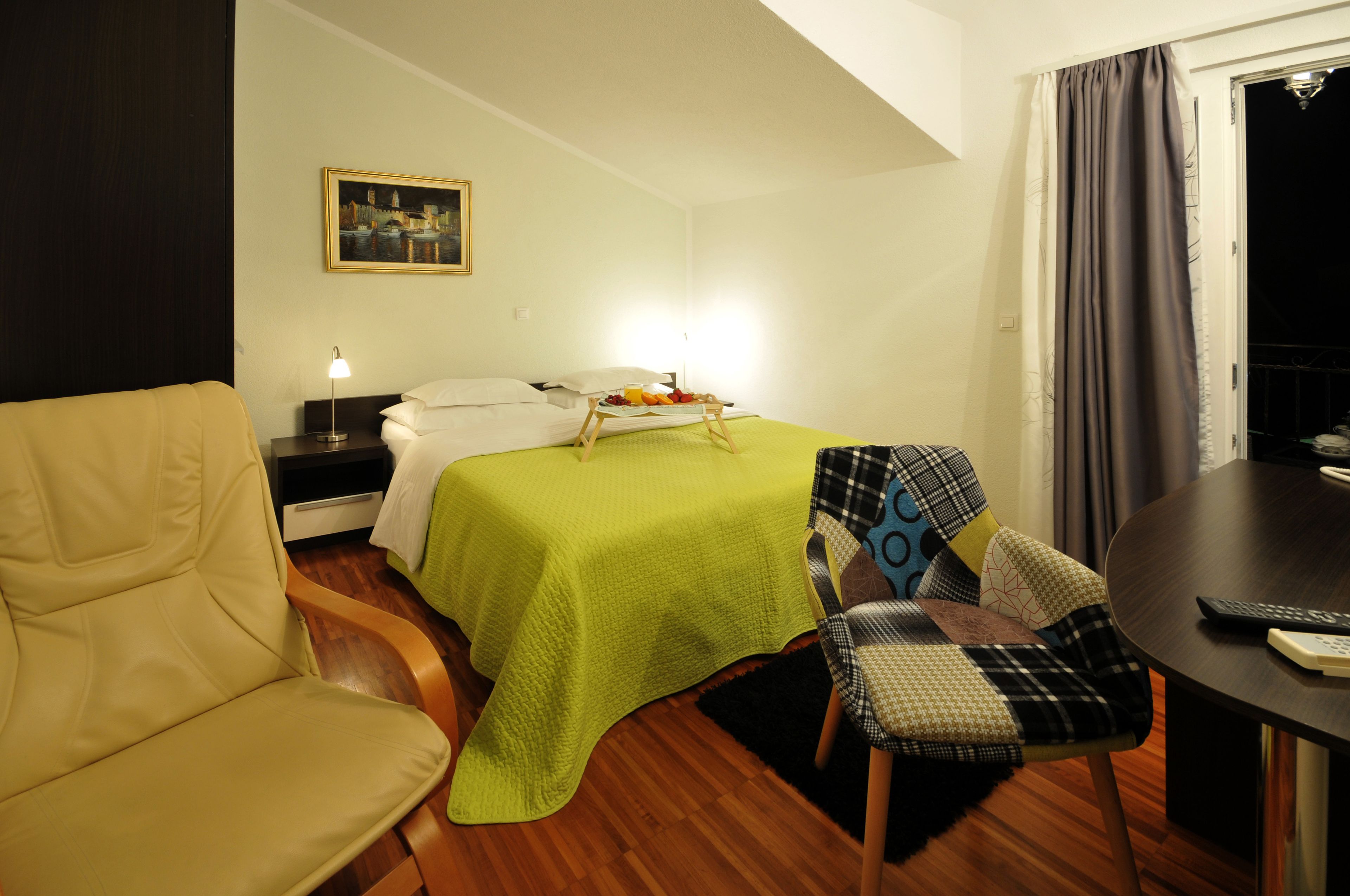 Ein Hotelzimmer mit Bett, Sessel, Tisch und einem Gemälde an der Wand.