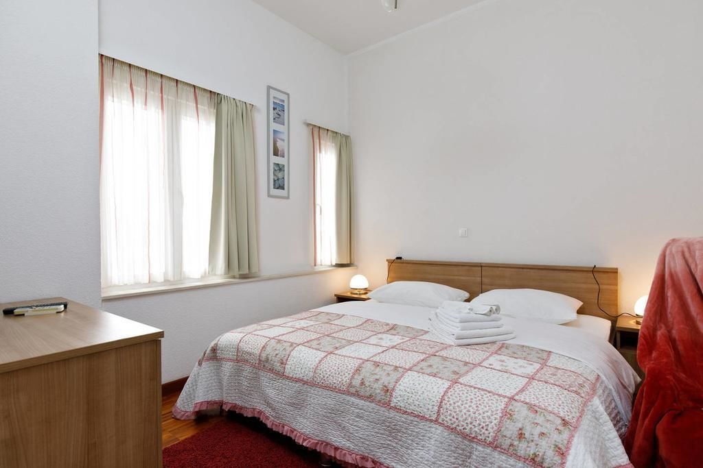 A neatly arranged bedroom with a bed, bedside table, and a desk.