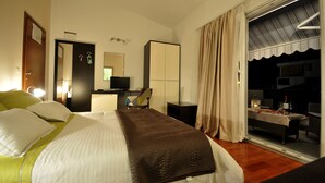 Une chambre d’hôtel équipée d’un lit, d’un bureau, d’une chaise, d’une télévision et d’une fenêtre avec des rideaux.