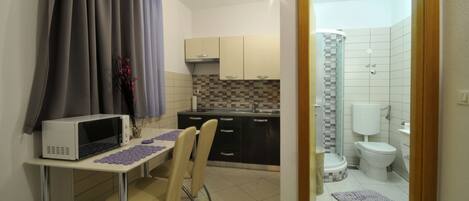 A compact kitchen with a microwave, a small dining table, and chairs.