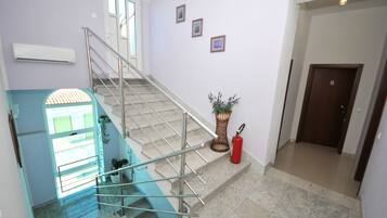 A staircase with a metal railing, a potted plant, and a fire extinguisher.