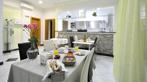 Un coin repas moderne, avec une table mise pour le petit-déjeuner, comprenant des fruits, du pain et des boissons.