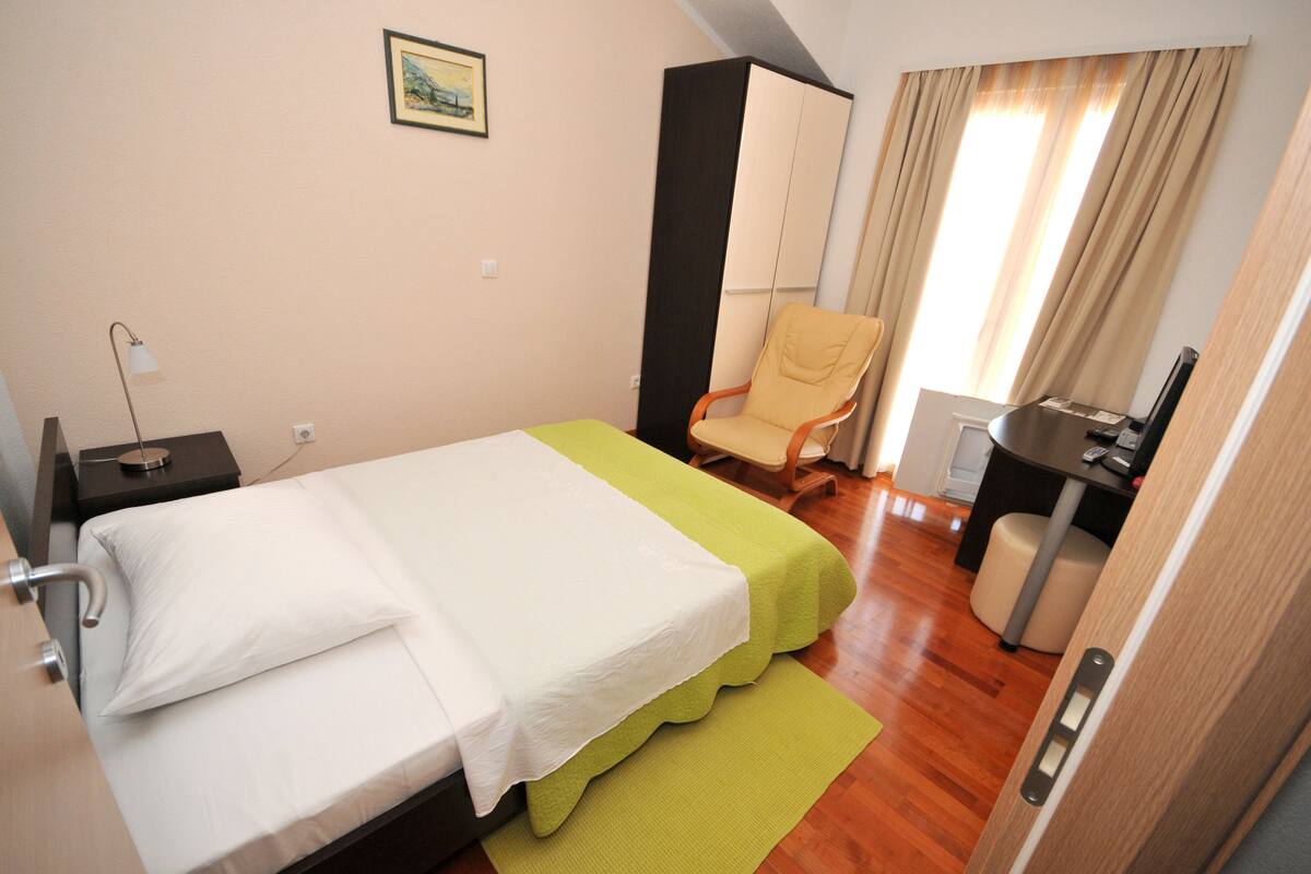 Een hotelkamer met een bed, een stoel, een bureau en een kledingkast.