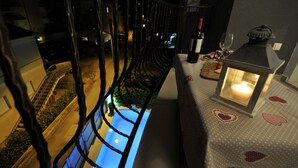 Un balcon donnant sur une piscine, avec une table agrémentée d’une bougie et d’une bouteille de vin.
