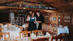 Una sala menjador de fusta tradicional, amb taules preparades per a dinar, cadires de fusta i diverses safates i utensilis a les prestatgeries.