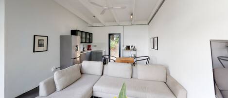 A modern living room with a sectional sofa, a dining area, and a kitchen.