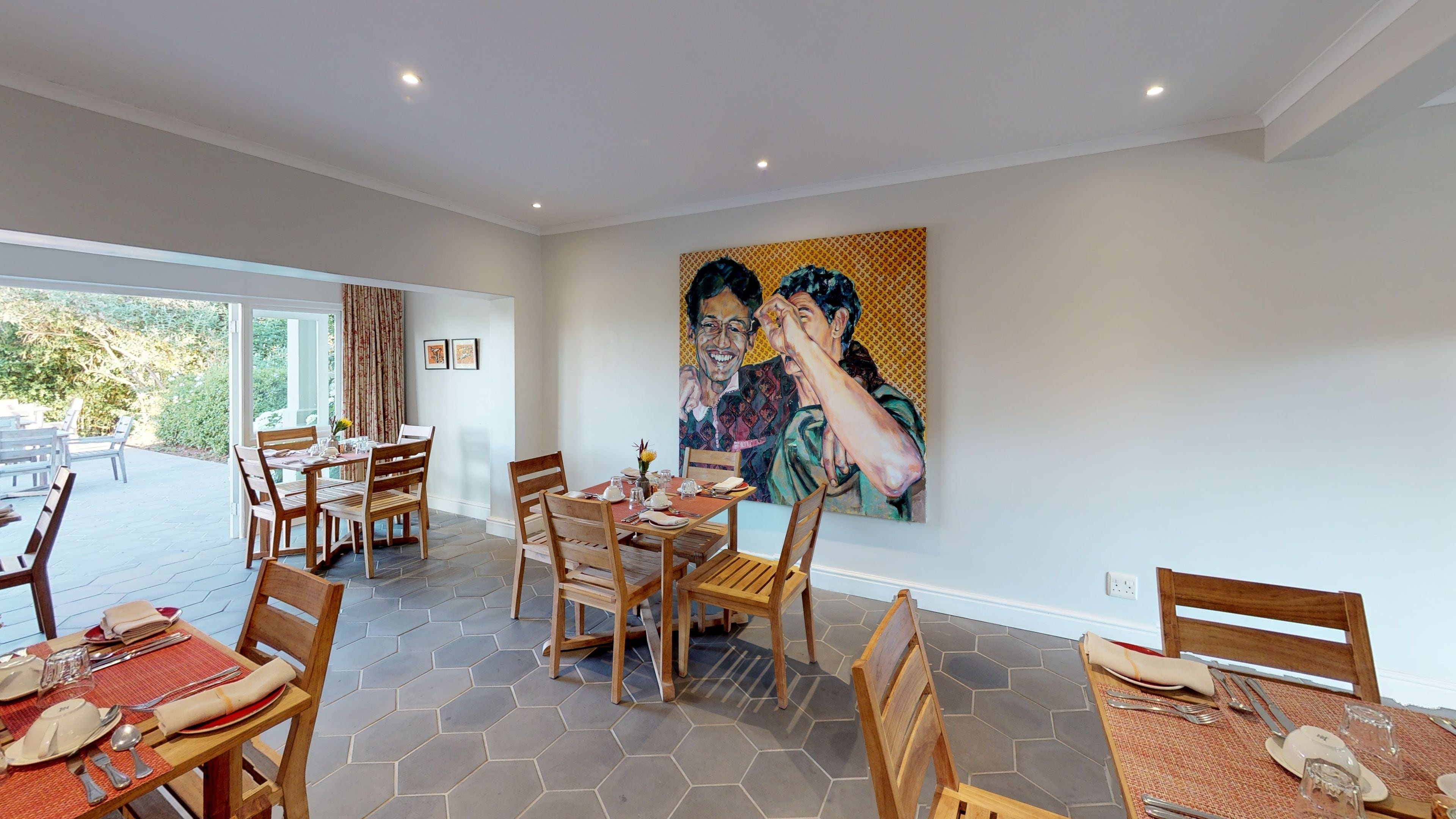 A dining area with hexagonal patterned flooring, wooden chairs, and tables set for a meal.