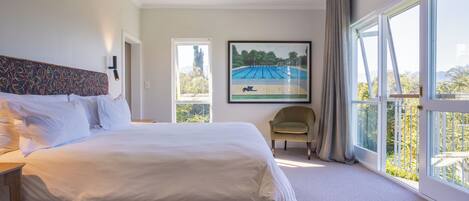 Une chambre d’hôtel avec un grand lit, une chaise, un tableau et une vue sur une piscine.