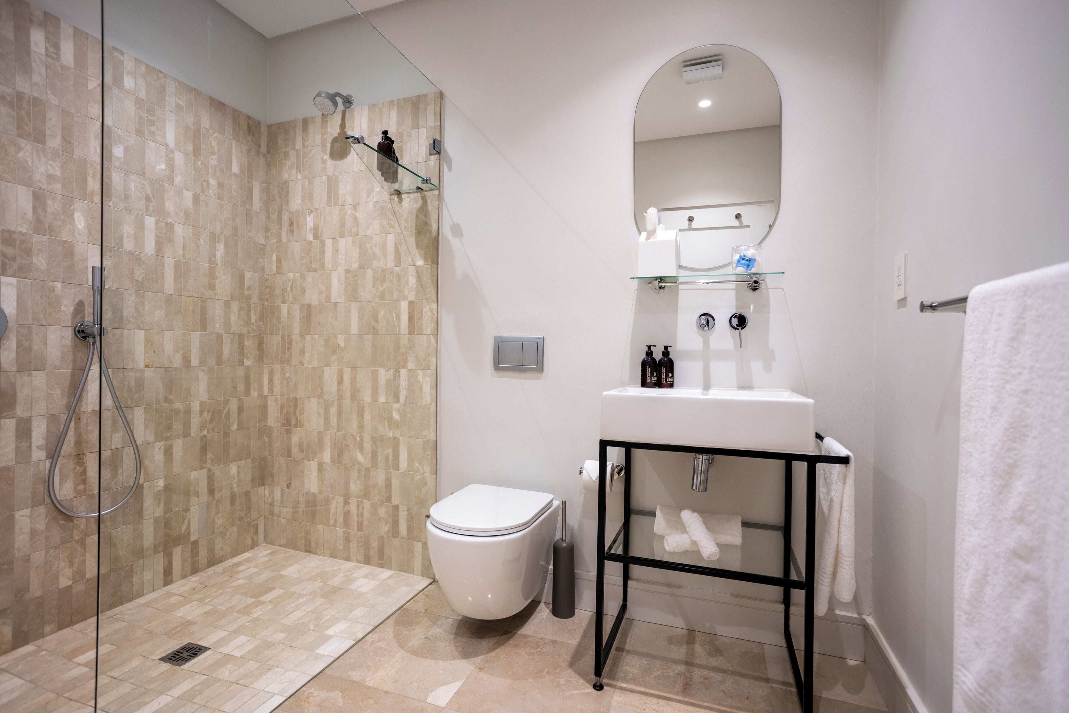 A modern bathroom with a glass-enclosed shower, a white toilet, a sink with a mirror, and a towel rack.