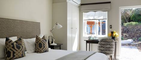 A neatly arranged bedroom with a large bed, a bedside table with a lamp, and a chair.