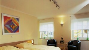 A hotel room with a double bed, a small table with two chairs, and a painting on the wall. - Hotel Veltrup (Laer)