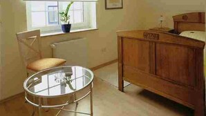 A room with a window, a radiator, a wooden cabinet, a chair, and a table. - Hotel Veltrup (Laer)