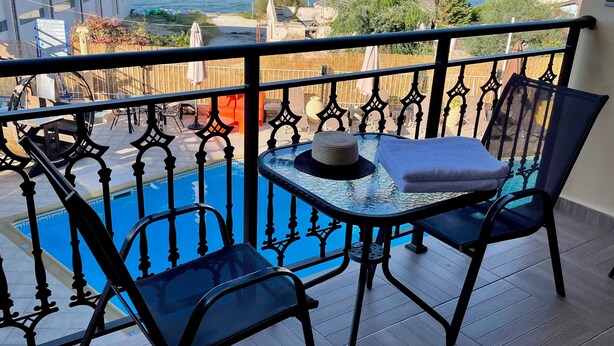 Un balcón con piscina, dos sillas y una mesa.