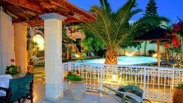 Una piscina al aire libre, sombrillas, sillones reclinables de piscina