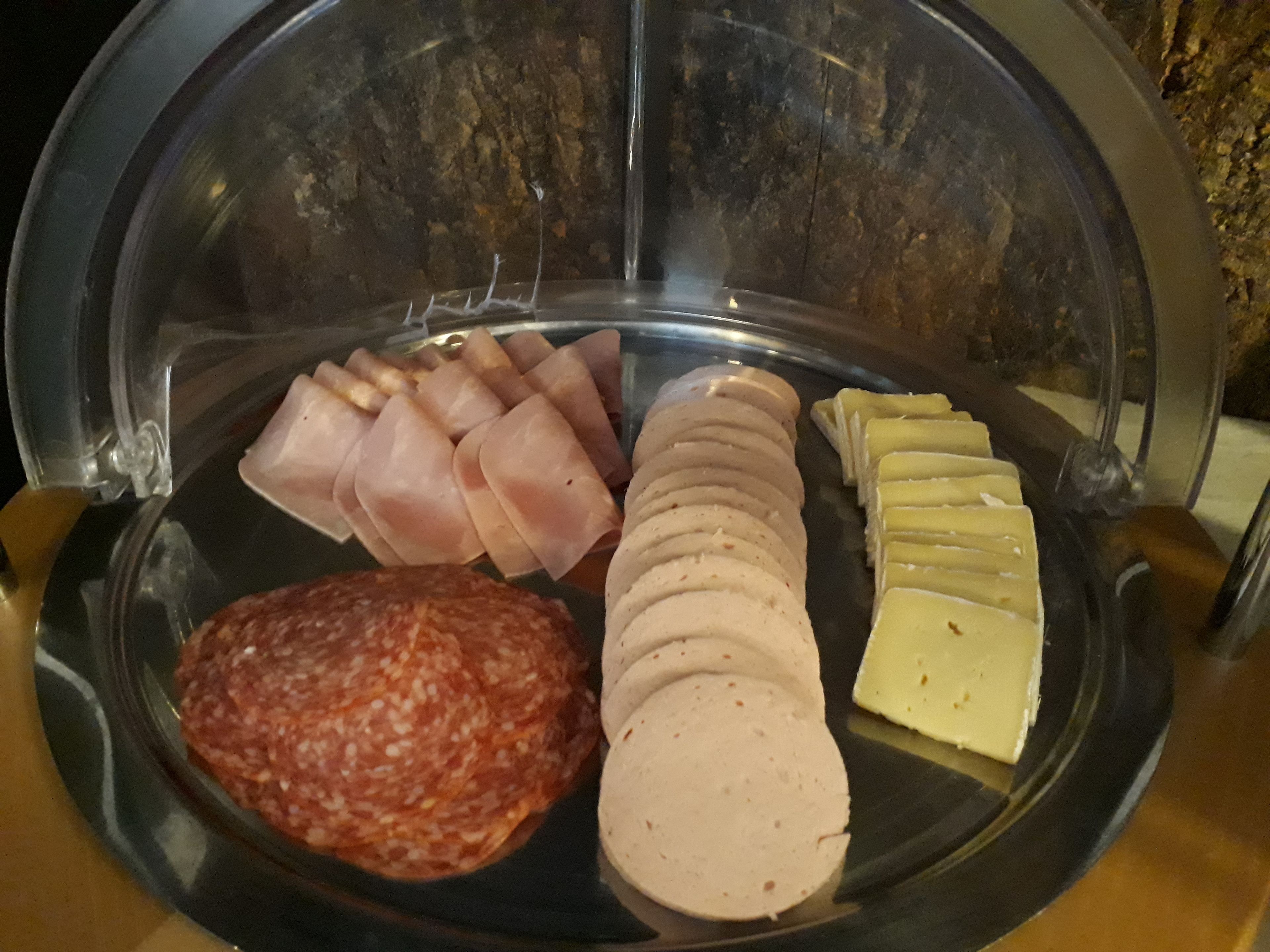 A glass display case containing various food items, including sliced meats and cheese.