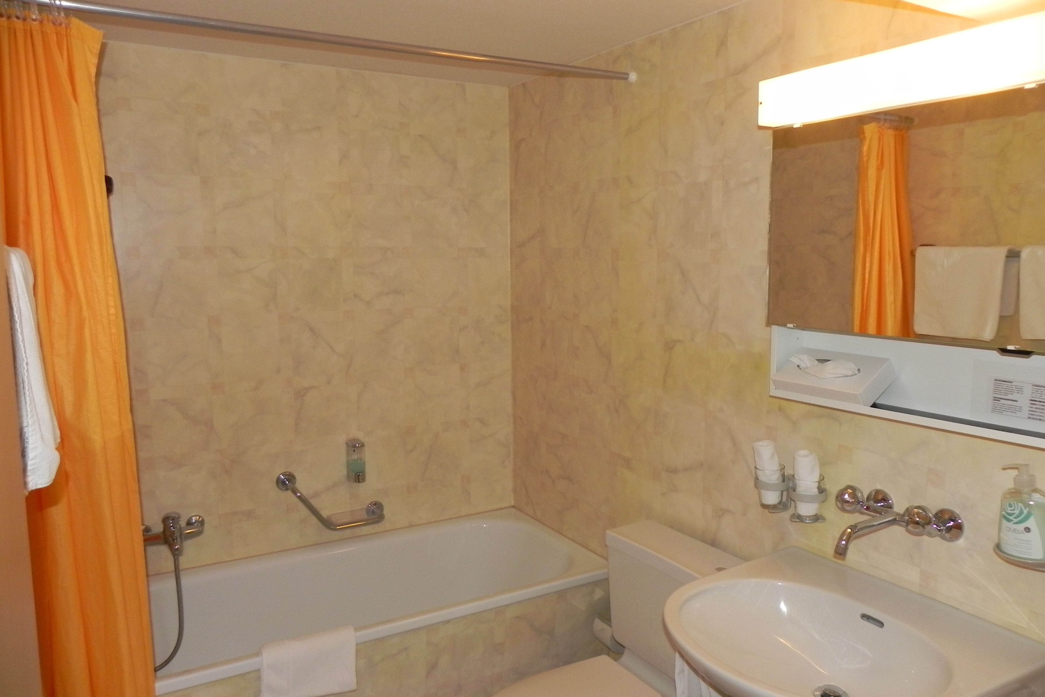 A bathroom with a bathtub, a sink, and a mirror.