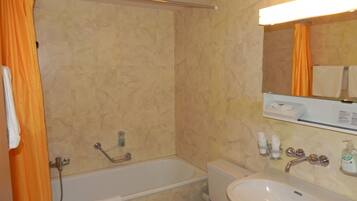 A bathroom with a bathtub, a sink, and a mirror.
