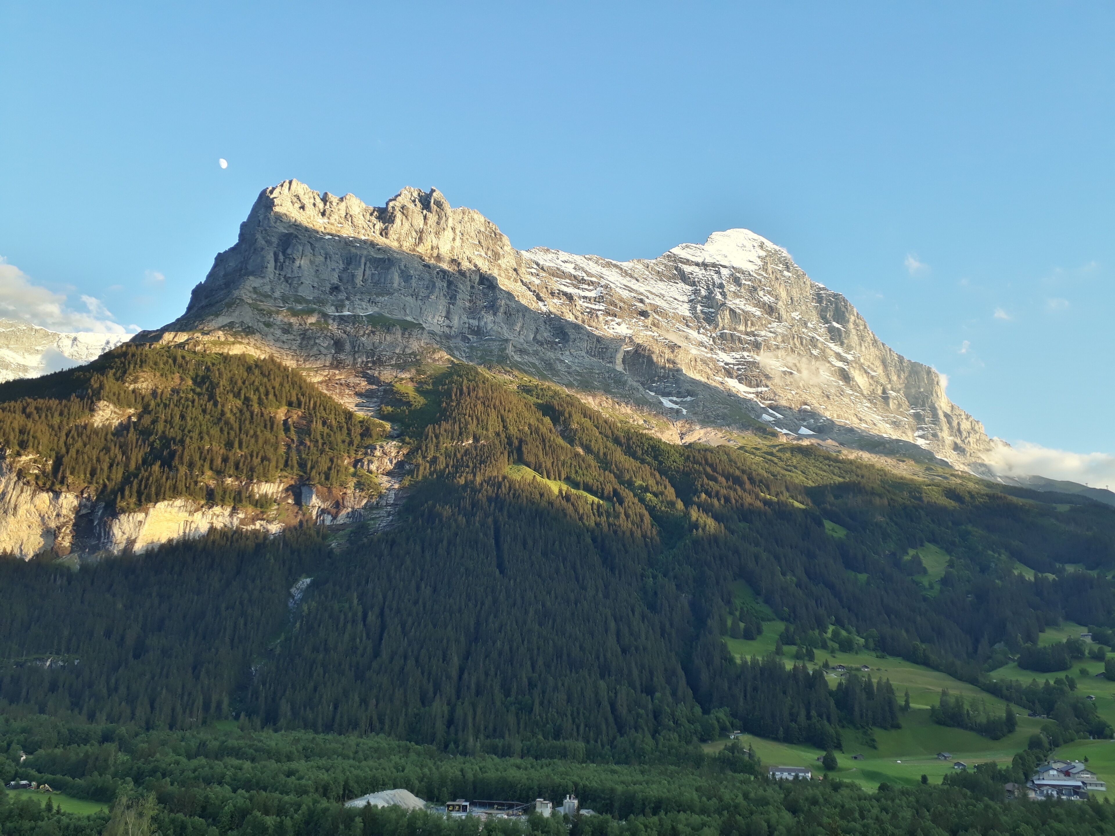 Ein Berg mit einem markanten Gipfel, dichten bewaldeten Hängen und einer kleinen Siedlung am Fuße.