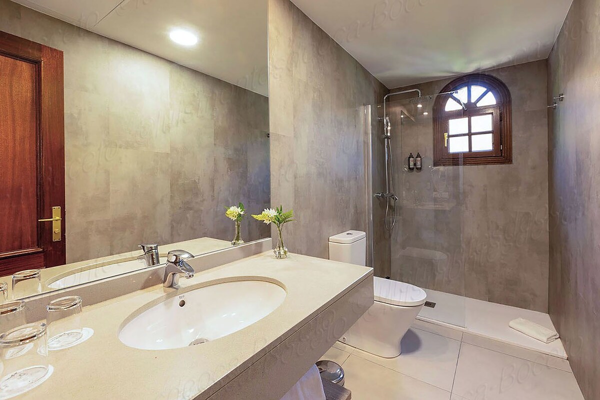 A bathroom with a large sink, mirror, and shower.